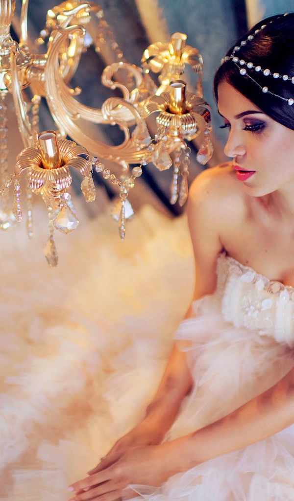 Молодая девушка в белом платье у красивой  люстры
