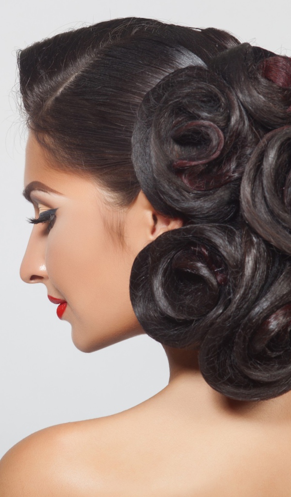 Молодая девушка с красивой прической на сером фоне