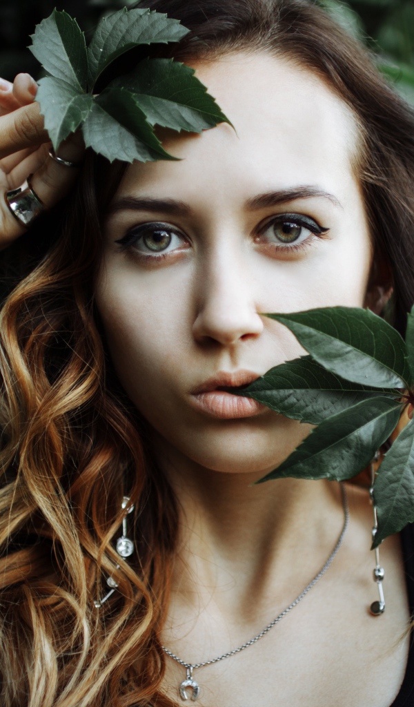 Молодая девушка с зелеными листьями в руках 