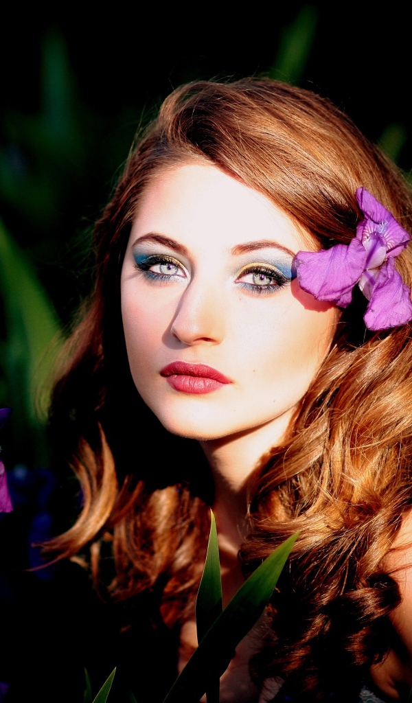 Молодая девушка с фиолетовым цветком ириса в волосах