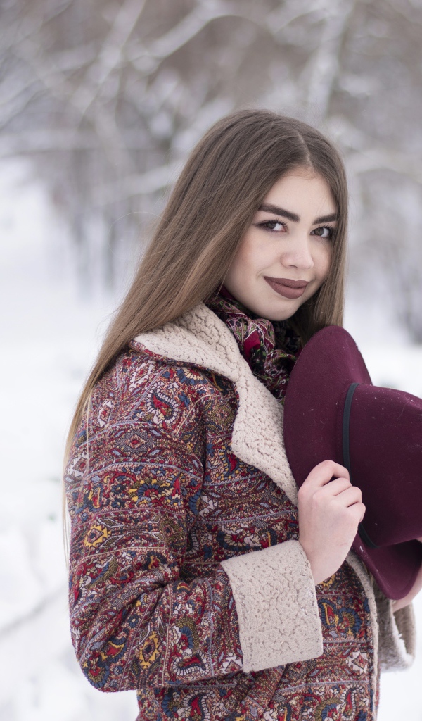 Молодая длинноволосая девушка шатенка с шляпой в руках зимой