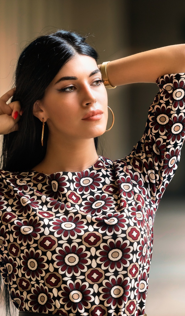 Молодая длинноволосая шатенка с руками в волосах