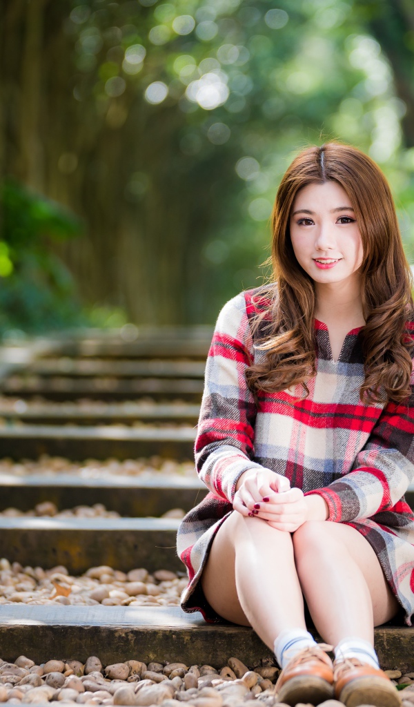 Молодая улыбающаяся азиатка сидит на дороге