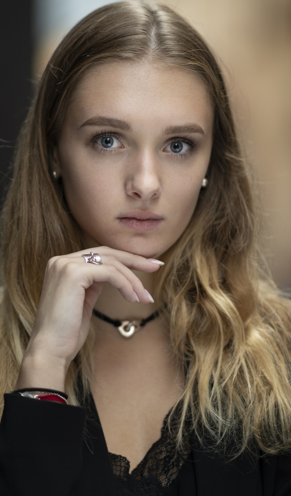 Молодая нежная голубоглазая девушка с рукой у лица