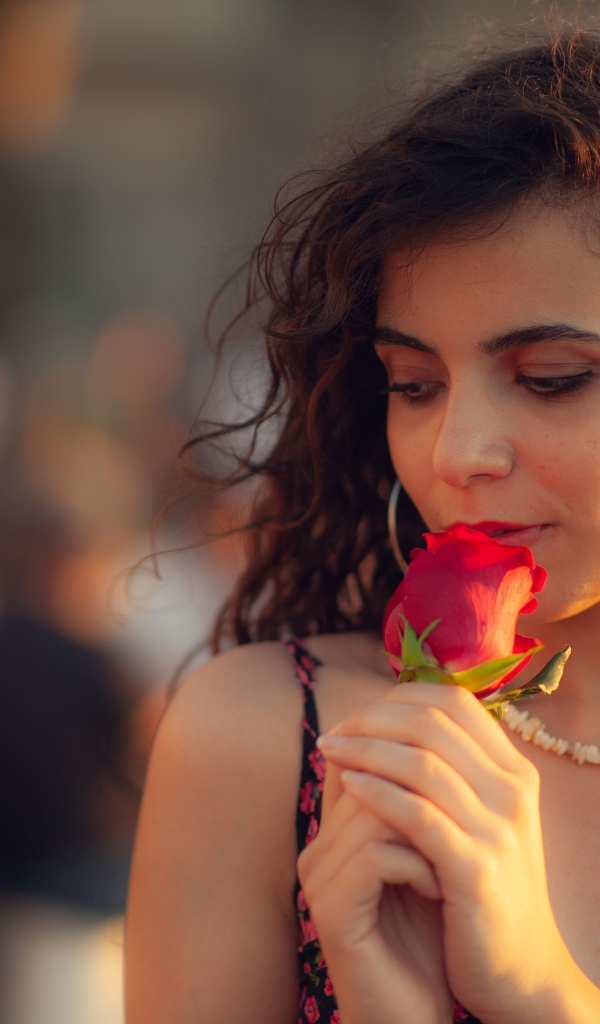 Молодая нежная девушка с красной розой в руке