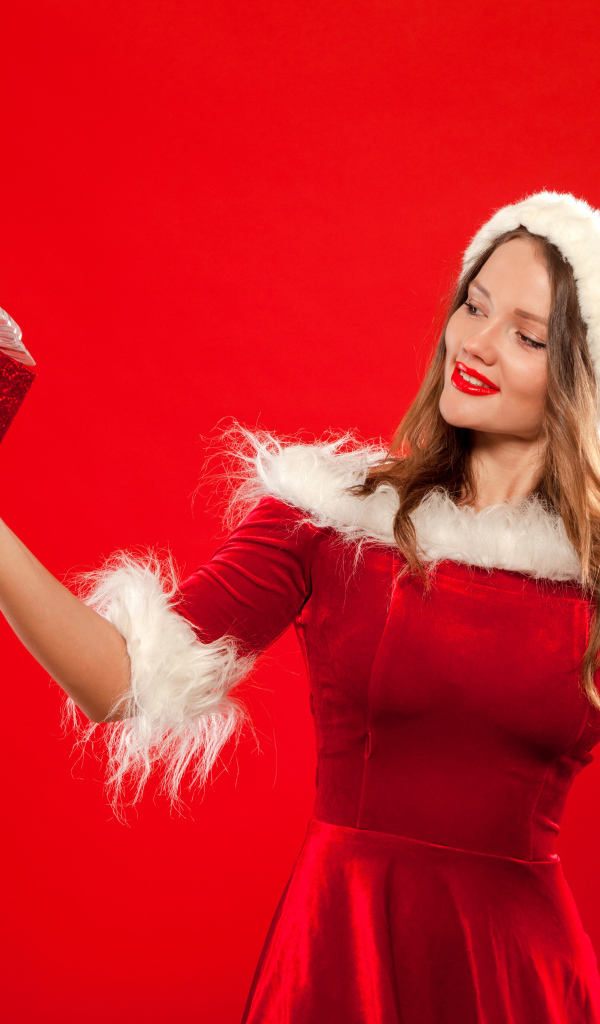 Красивая Снегурочка с подарком в руке на красном фоне