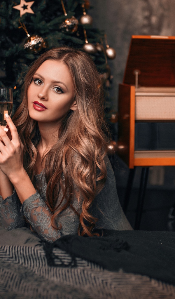 Красивая девушка с фужером шампанского у новогодней елки