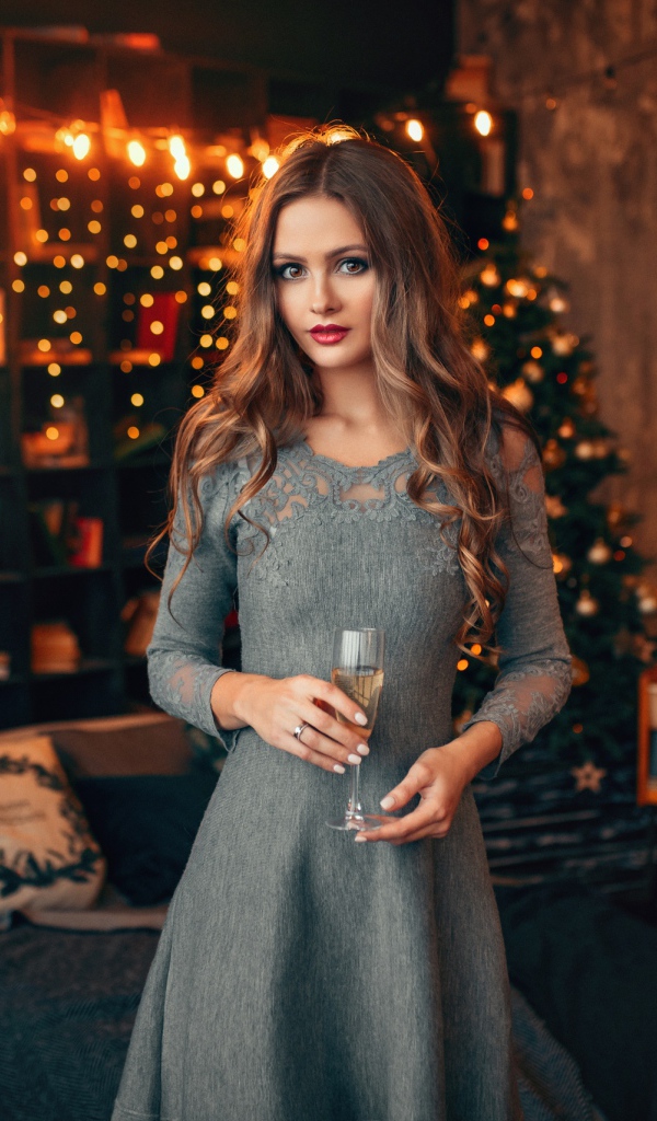 Beautiful girl with a glass of champagne in a room decorated with a garland