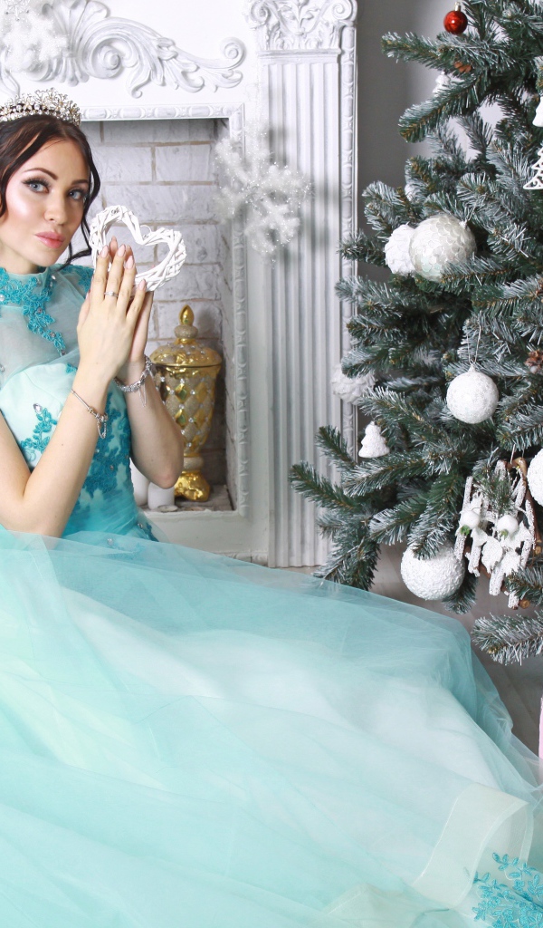 Молодая девушка в красивом голубом платье у новогодней елки