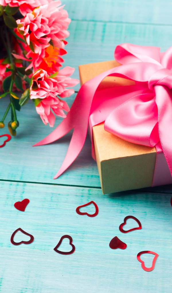 Подарок с розовым бантом на голубом столе с букетом