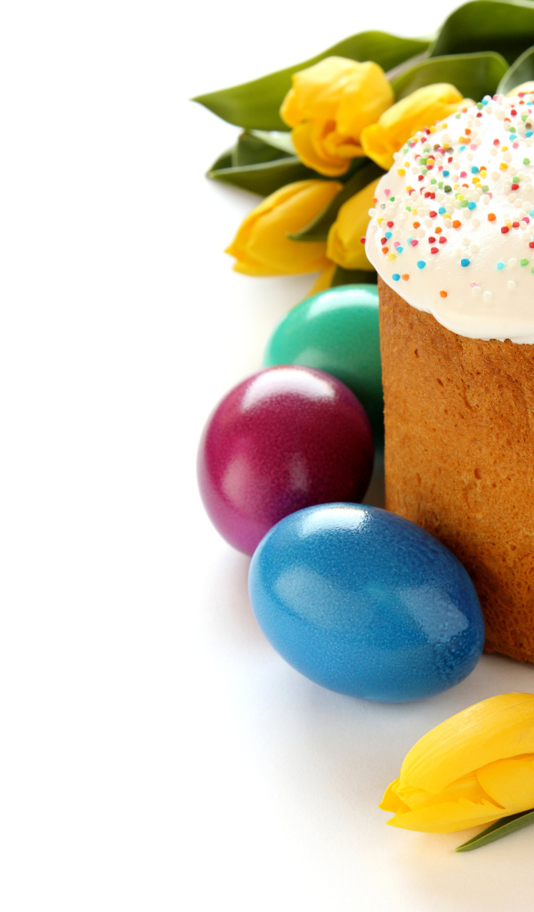 Красивый праздничный кулич с желтыми тюльпанами и крашеными яйцами на белом фоне к Пасхе