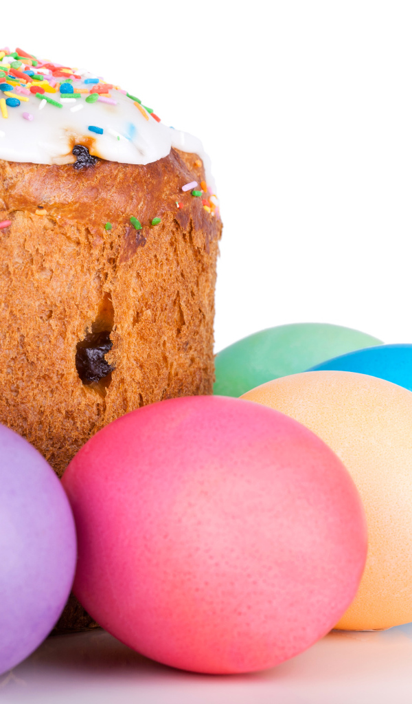 Пасхальный кулич с изюмом на белом фоне с крашеными яйцами 