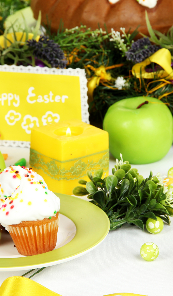 Накрытый пасхальный стол с кексами и зажженной свечой 