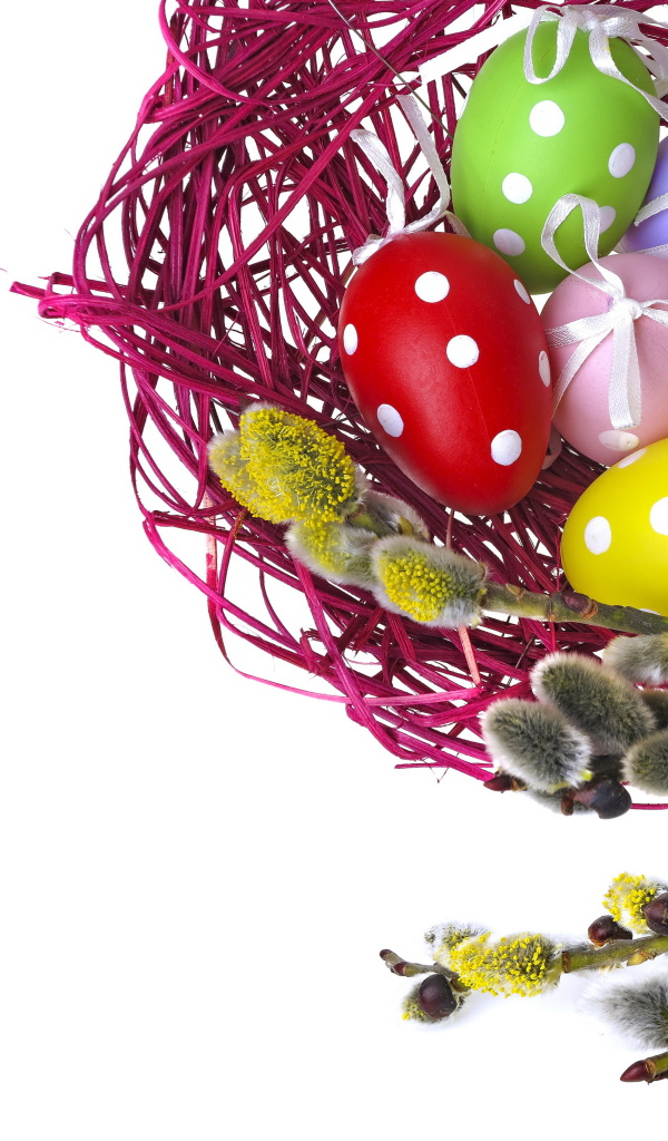 Крашеные пасхальные яйца в гнезде на белом фоне с веткой вербы