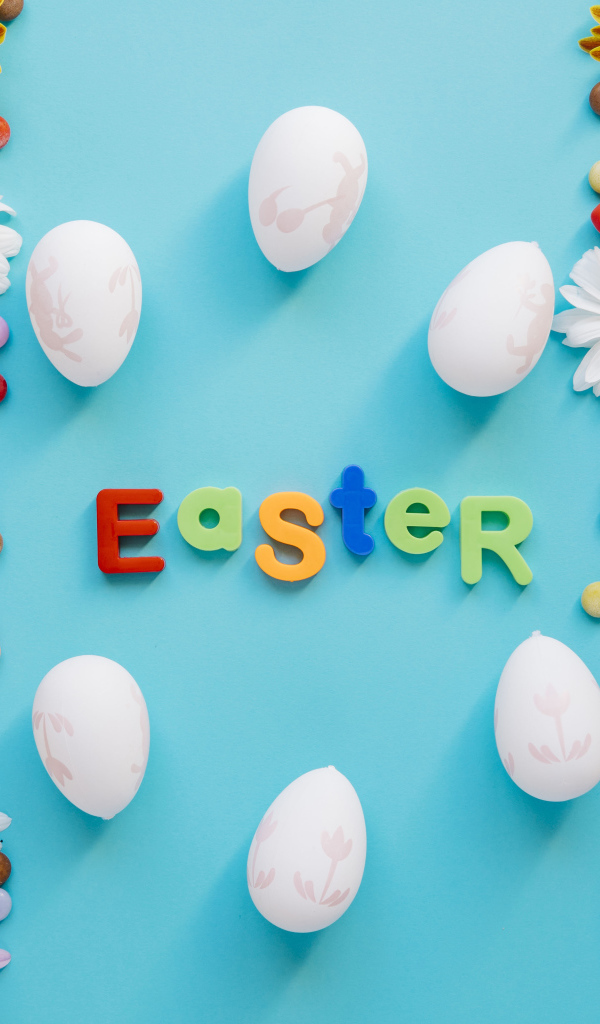 Надпись Пасха на английском на голубом фоне с конфетами и яйцами