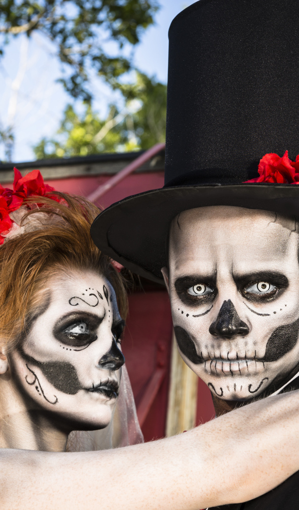 Пара жених и невеста с масками с грима на лице на Хэллоуин 