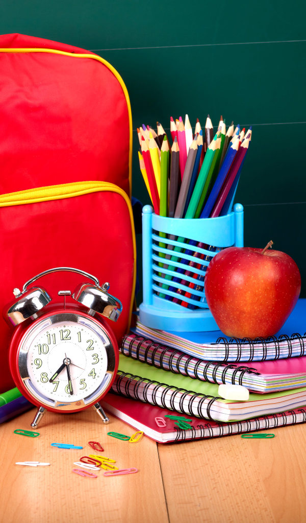 Рюкзак, тетради, карандаши, будильник и яблоко на День знаний 1 сентября