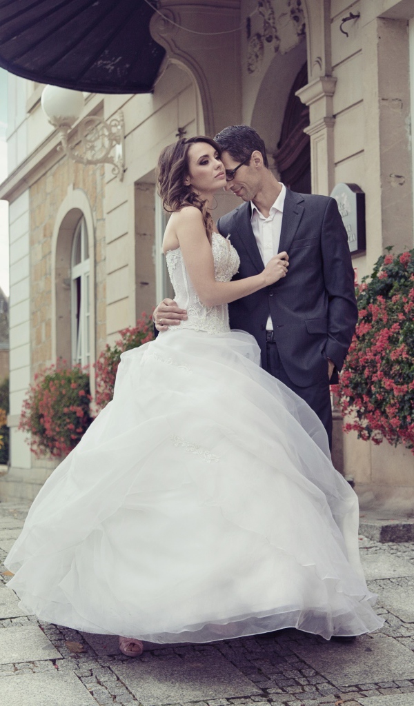 Жених и невеста стоят у здания 