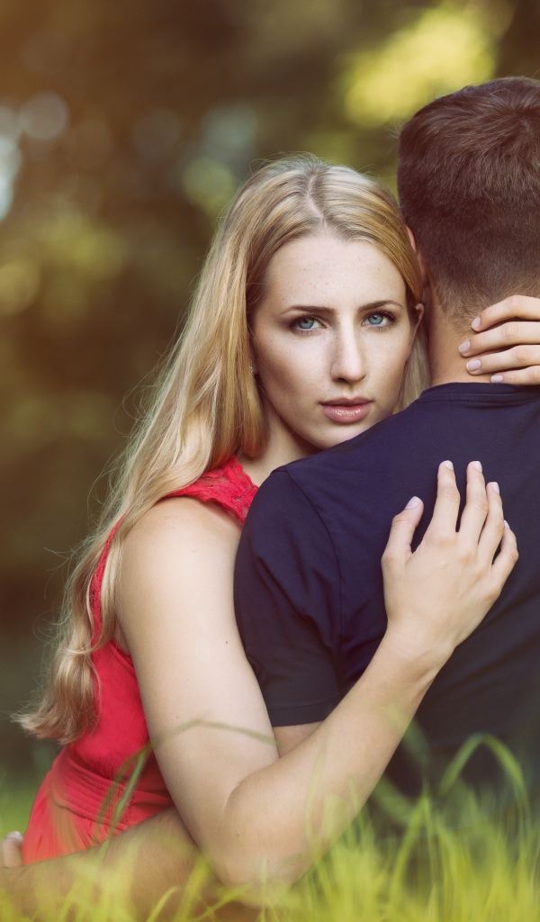 Красивая девушка обнимает парня сидя на траве