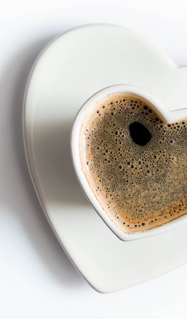 Красивая белая чашка в форме сердца с кофе на белом фоне