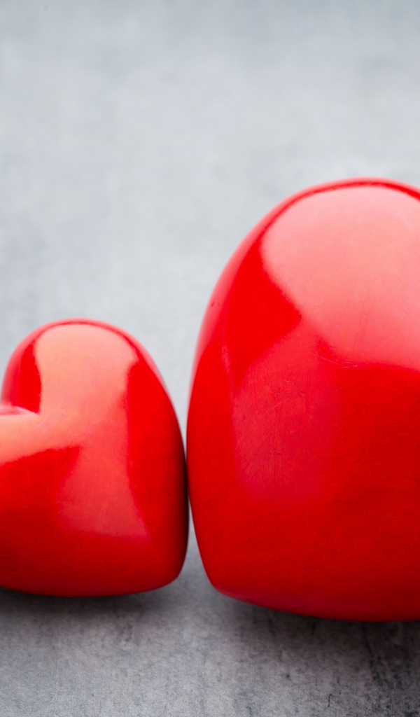 Большое и маленькое красное сердце на сером столе