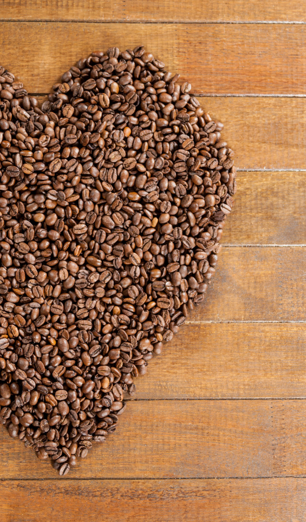 Большое сердце из кофейных зерен на деревянном столе