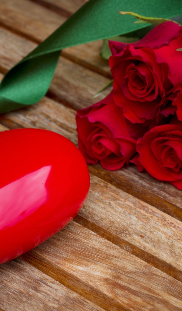 Большое сердце на деревянном столе с букетом красных роз 