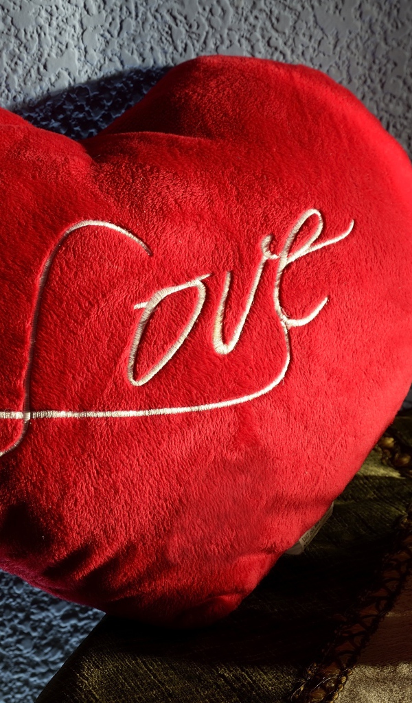 Большое плюшевое красное сердце у стены 