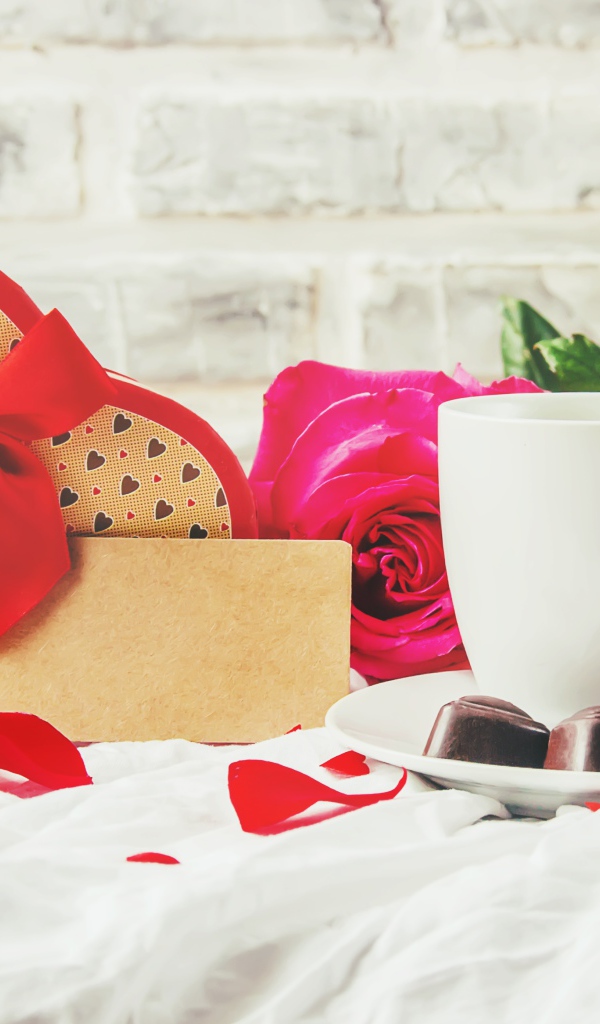 Коробка с подарком на столе с чашкой кофе и красными розами 