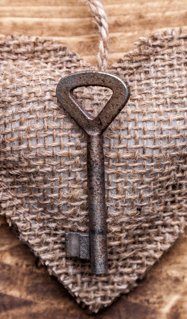 Сердечко из мешковины с ключом на деревянном фоне