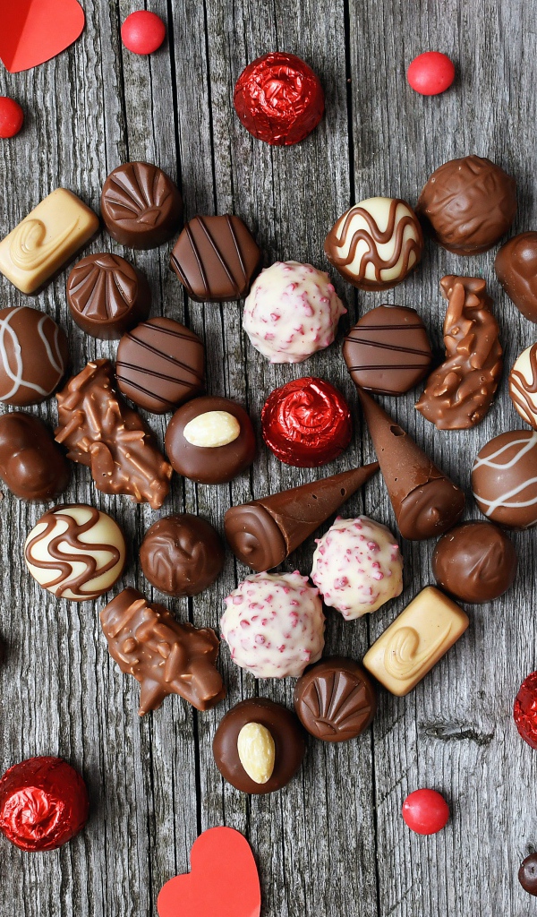 Сердце из шоколадных конфет ассорти на деревянном столе для любимой 