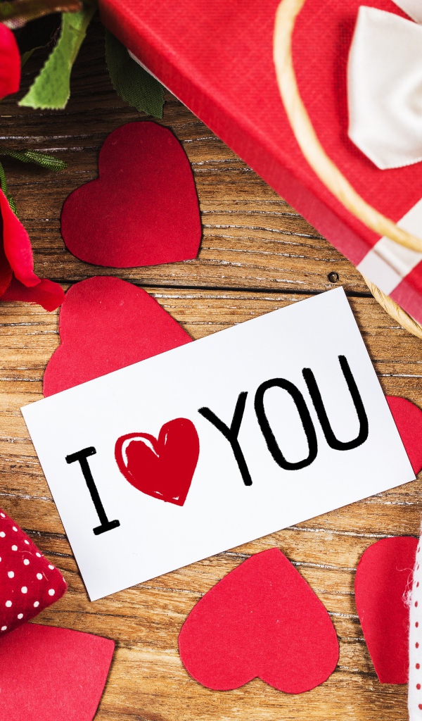 Сердечки, цветы и подарок на столе с запиской