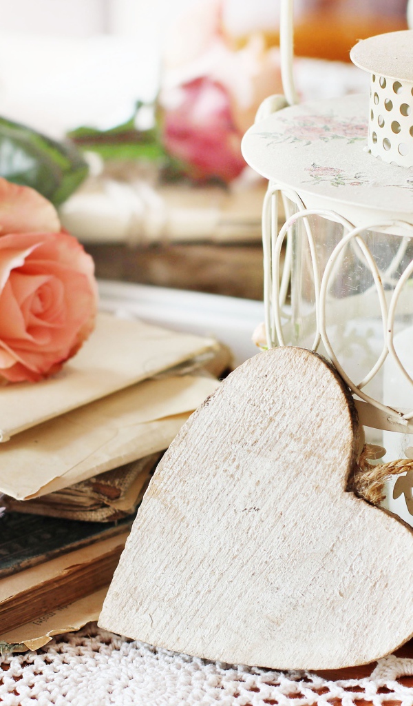 Фонарь со свечей на столе с розой, сердцем и книгами