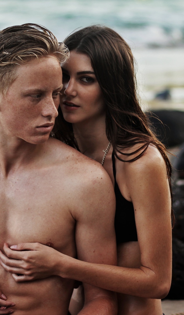 Влюбленная пара сидит на камнях на берегу моря 