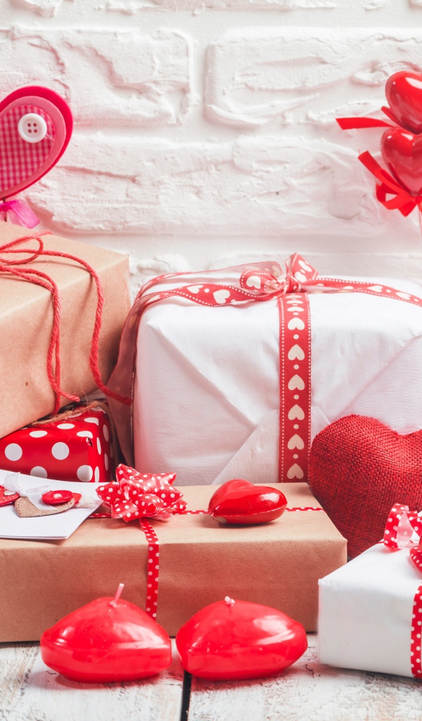 Много  подарочных коробок с сердечками на фоне стены