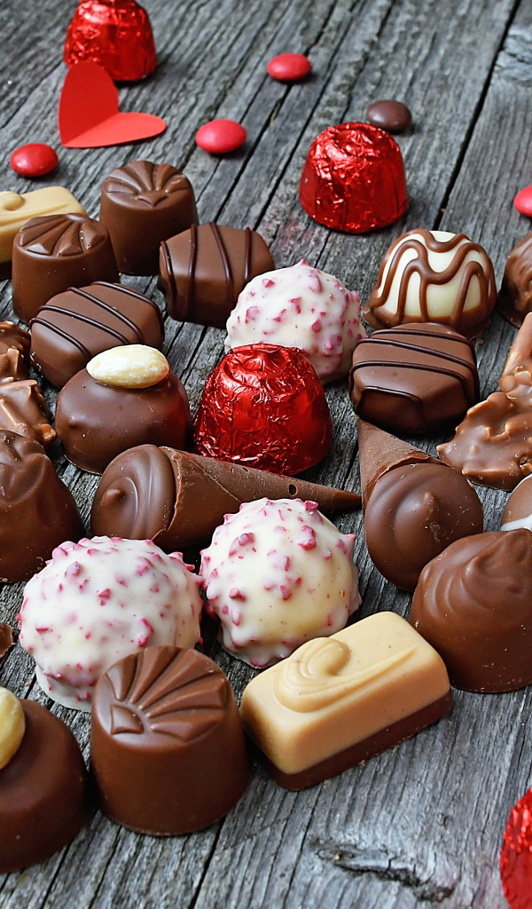 Сладкое сердце из шоколадных конфет на деревянном столе