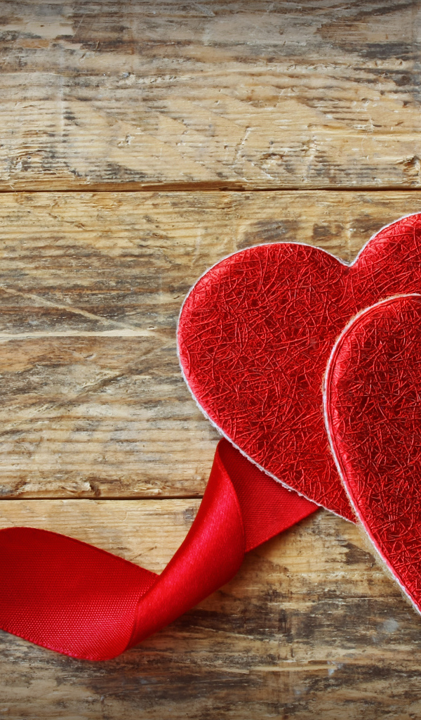 Два сердца с красной лентой на деревянном столе