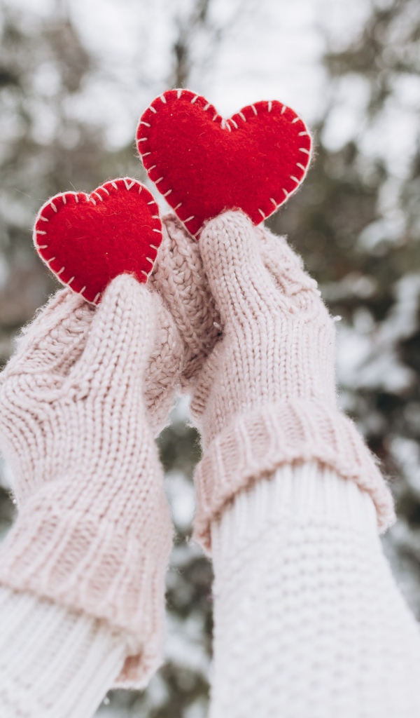 Два красных сердечка из ткани в руках у девушки 
