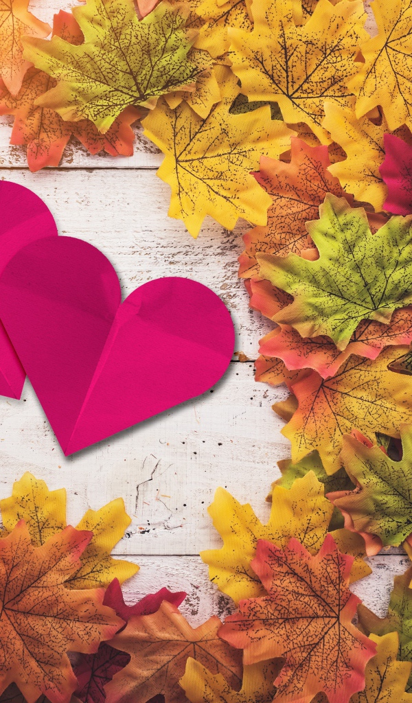 Два красных сердца на столе с желтыми листьями