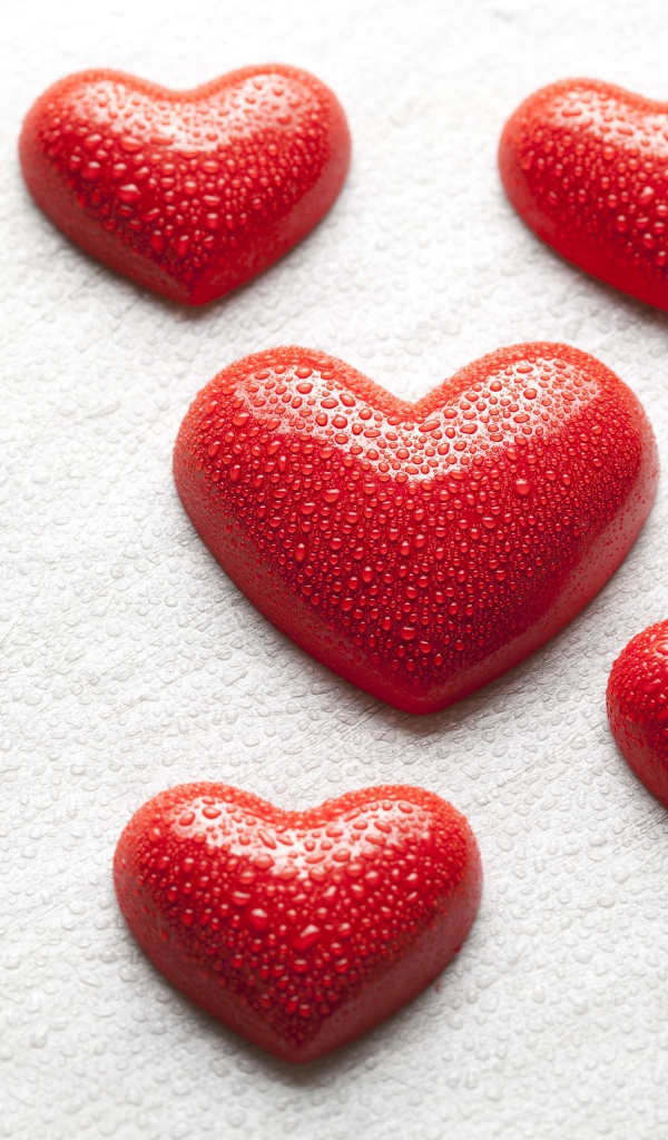 Мокрые красные сердечки на белой поверхности 