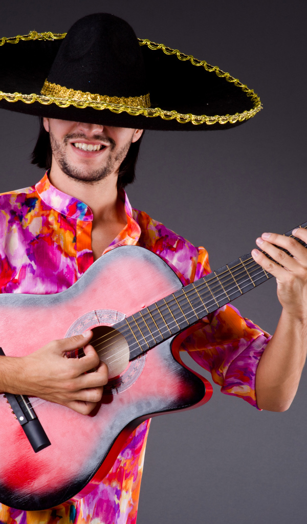 Мужчина в сомбреро с гитарой в руках на сером фоне