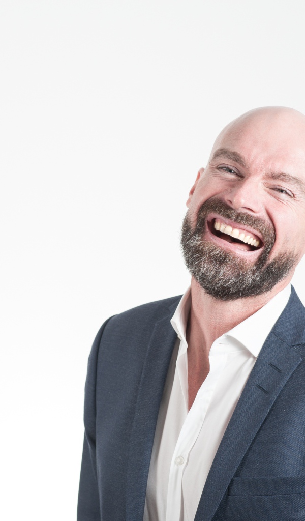 Смеющийся мужчина с бородой в костюме на сером фоне