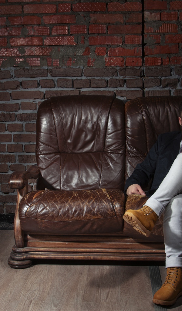 Стильный мужчина сидит в кожаном кресле 