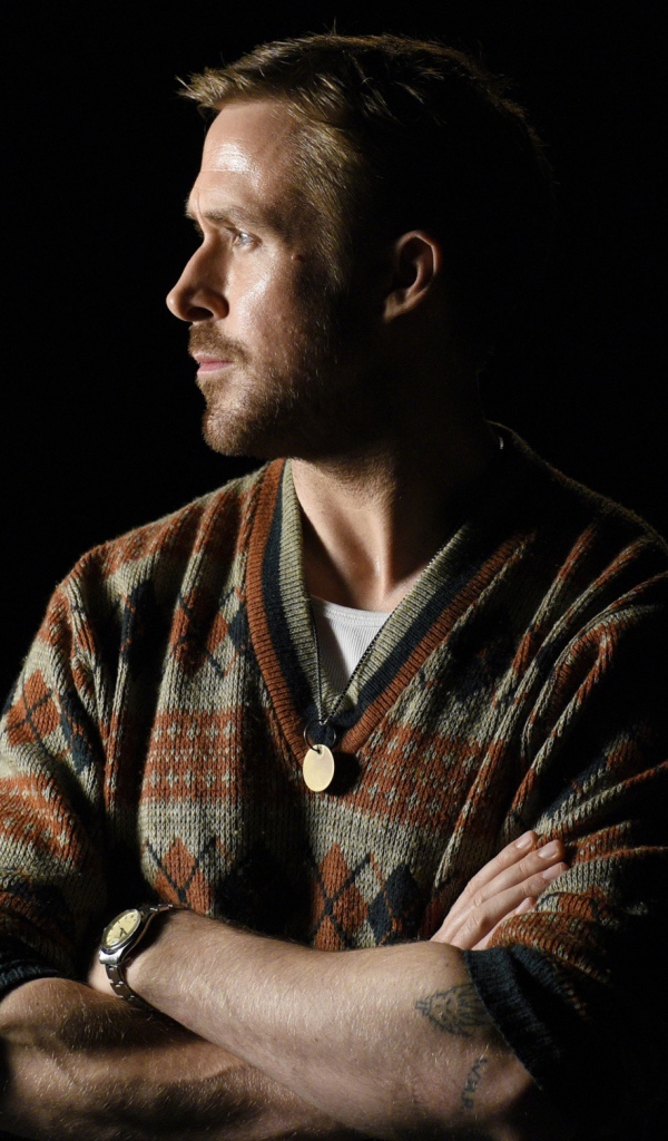 Актер Райан Гослинг в свитере на черном фоне 