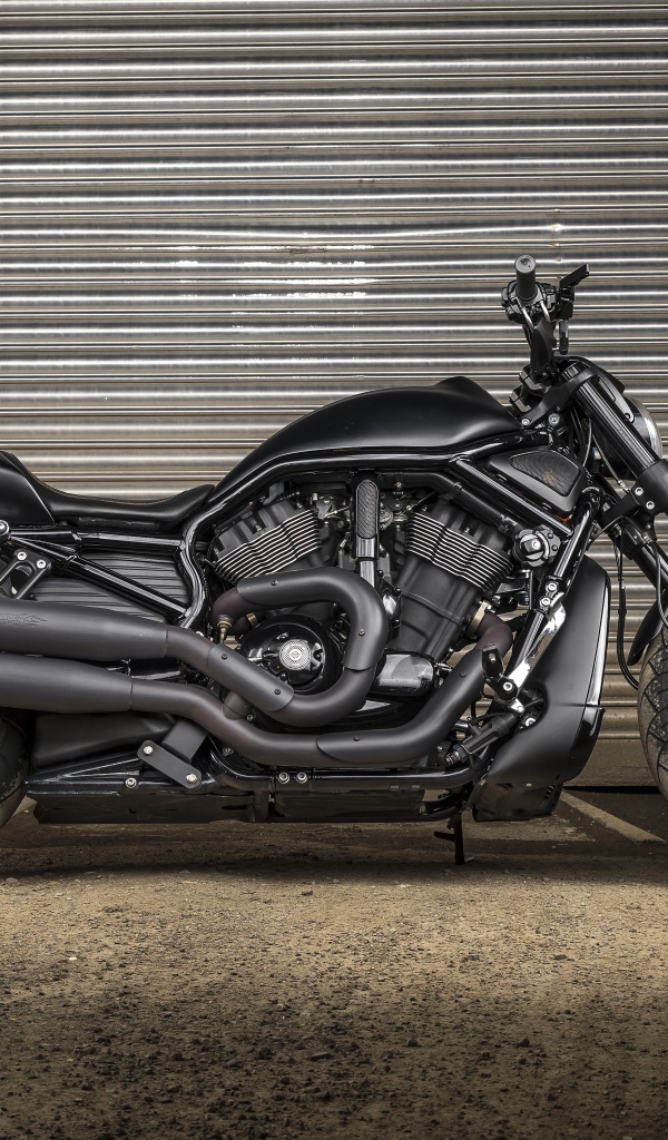 Черный тяжелый мотоцикл Harley-Davidson у гаража