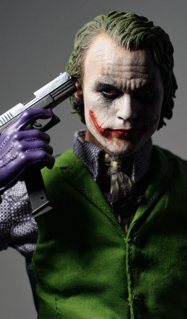 Персонаж Джокер с пистолетом в руке на сером фоне