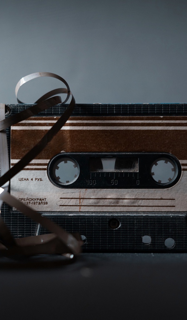 Старая кассета с вытянутой пленкой на сером фоне 