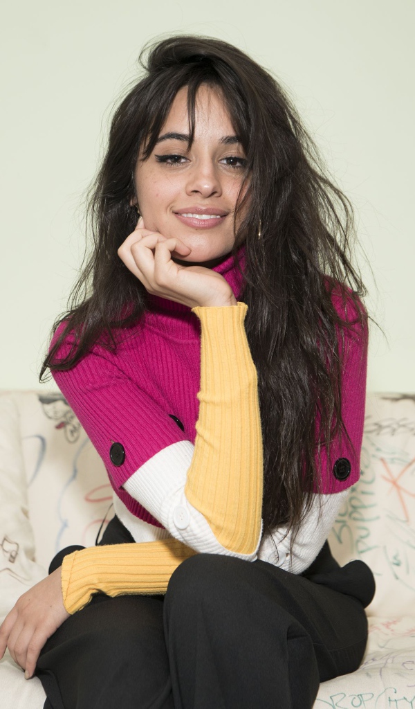 Улыбающаяся Камила Кабельо сидит на диване