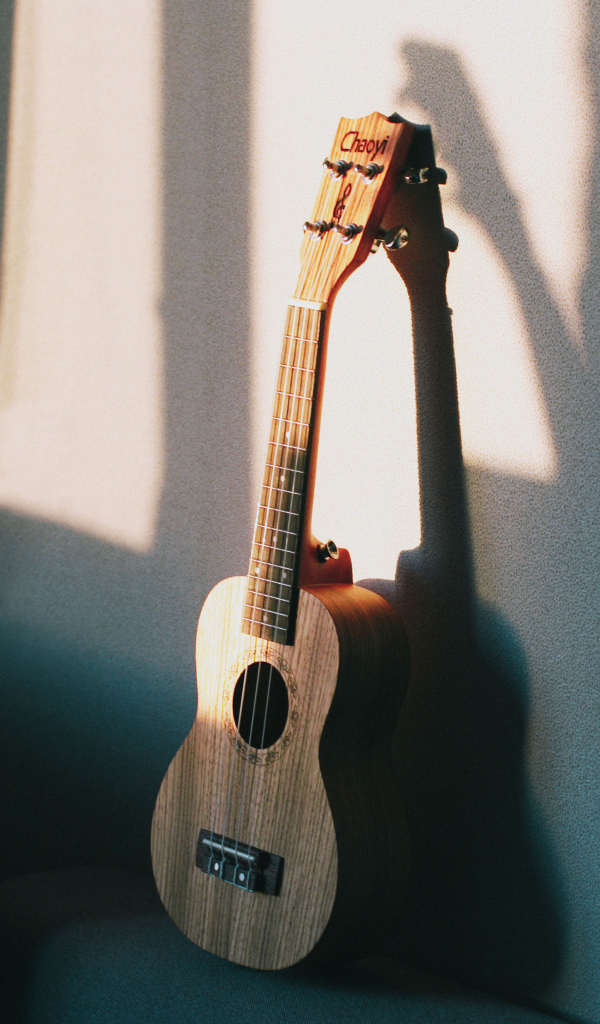 Желтая гитара стоит у серой стены