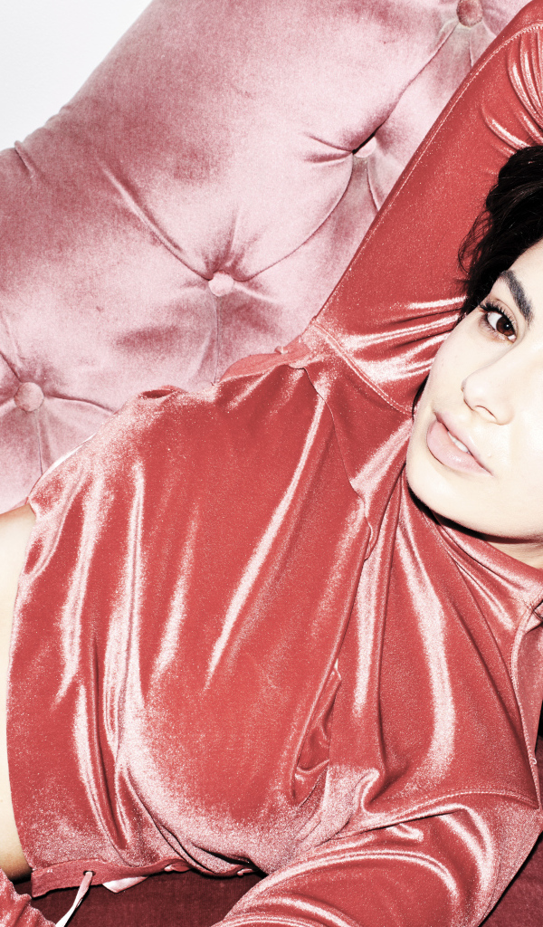 Молодая девушка Charli XCX лежит на диване